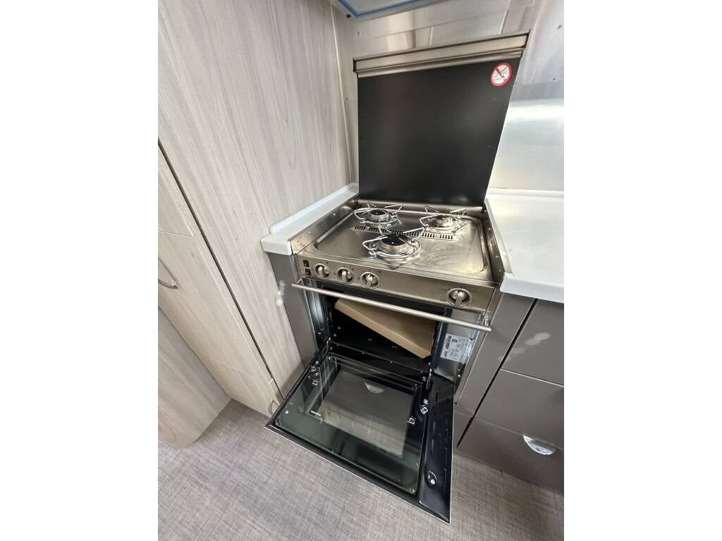 2021 Airstream Globetrotter 27FB Twin — stainless steel three burner cooktop and oven